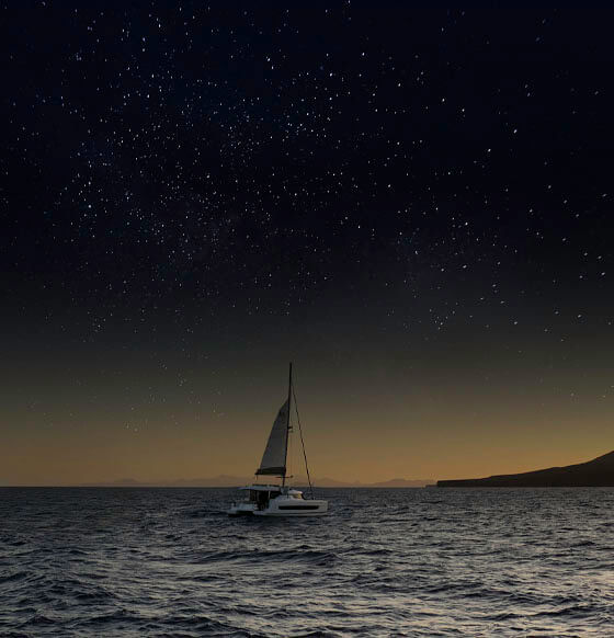 Velero navegando al atardecer bajo cielo estrellado, experiencia de conexión con la naturaleza