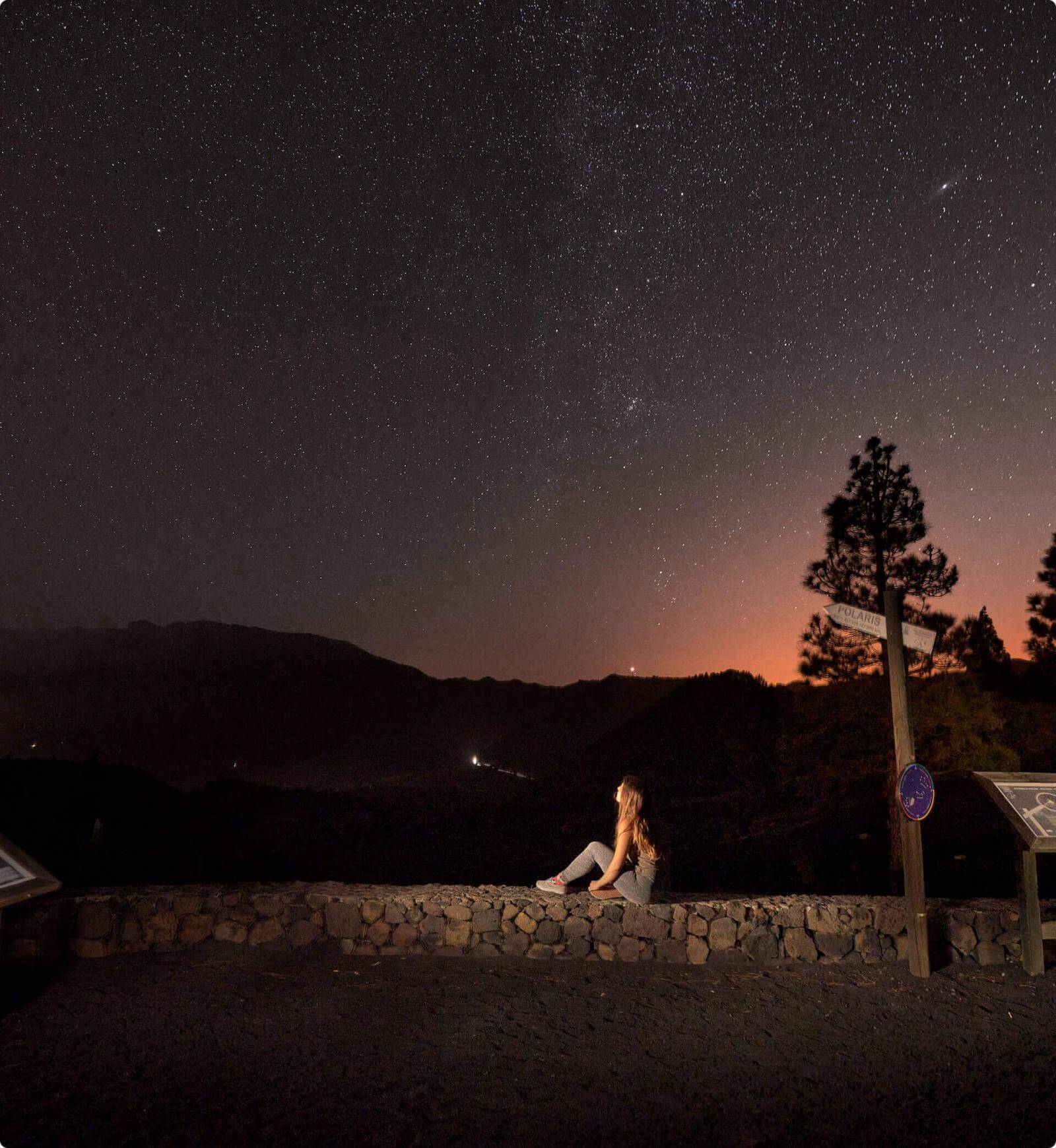 Nuit étoilée depuis le mirador Llano del Jable, à La Palma, avec des silhouettes de montagnes et une personne.