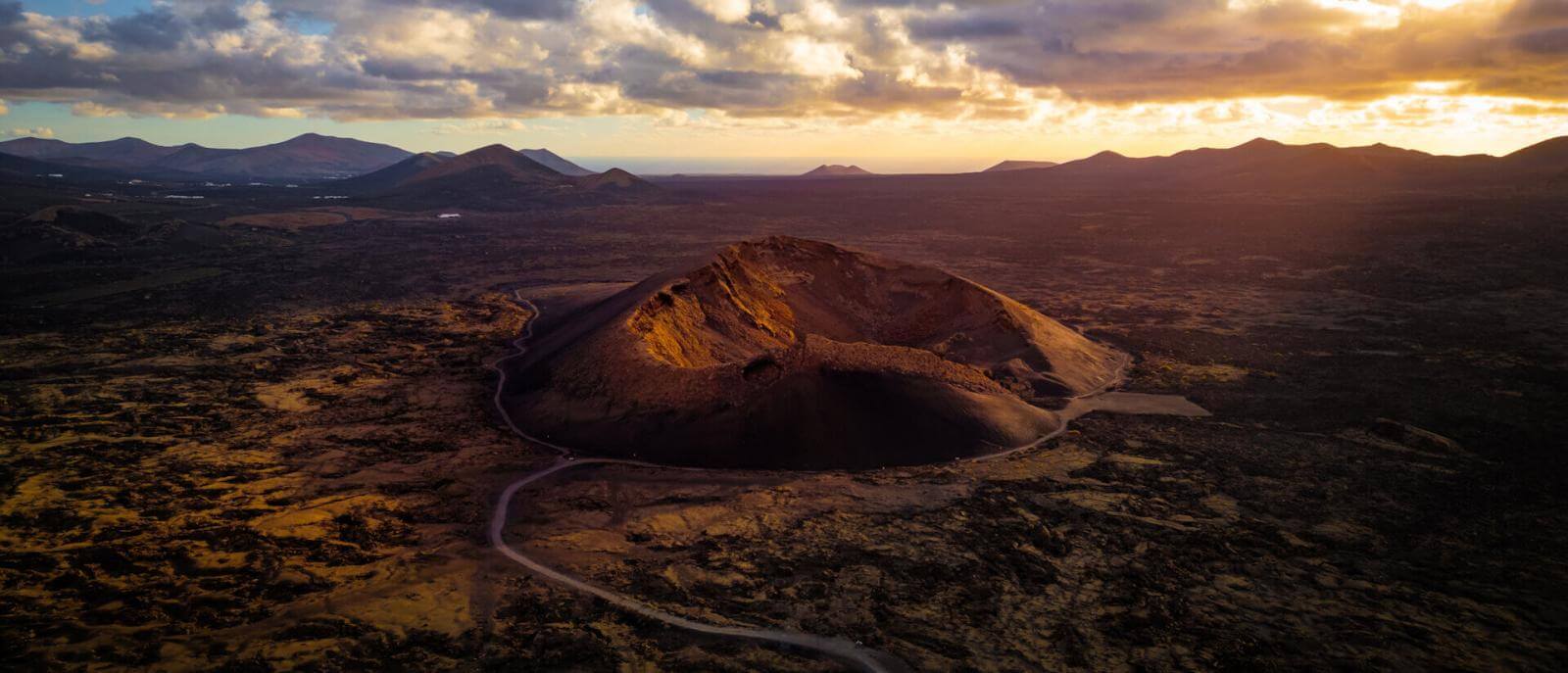 Vue aérienne du Volcan du Cuervo à Lanzarote, avec son cratère illuminé au coucher du soleil.