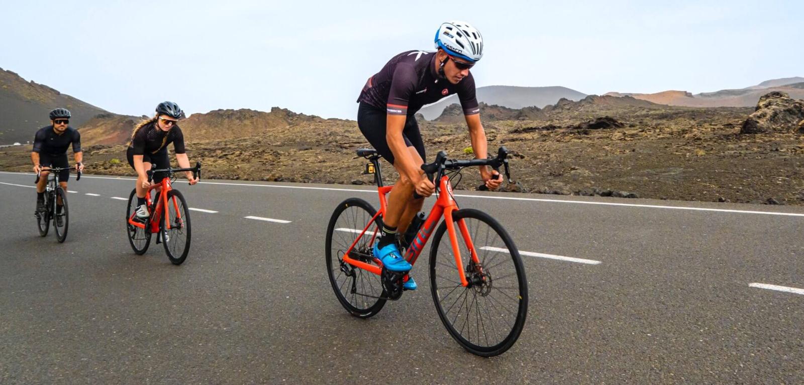 Coureurs cyclistes sur route lors d’une ascension dans un paysage volcanique.