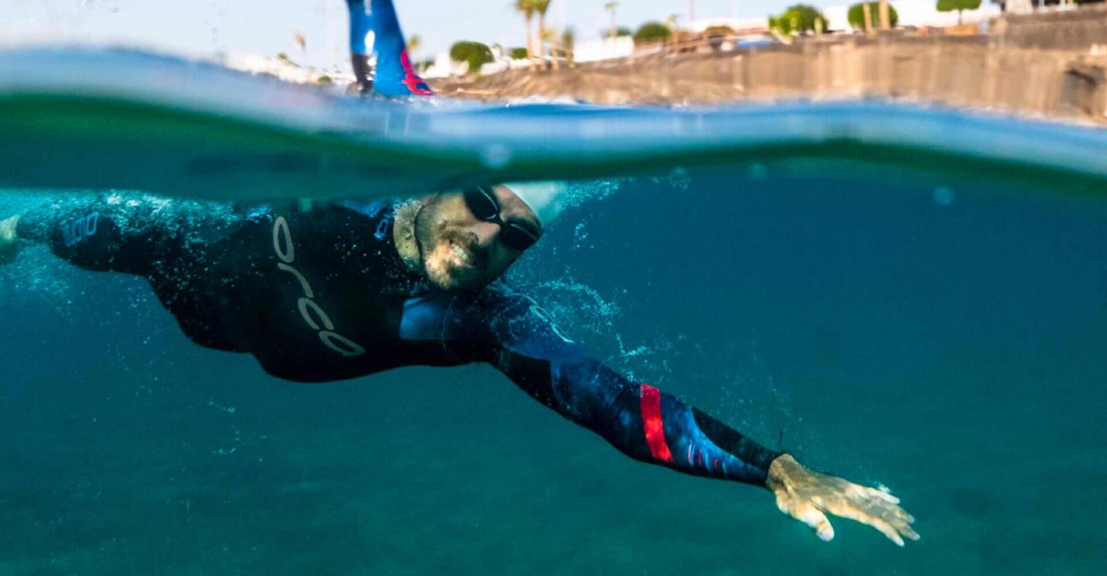 Personne nageant en eau libre avec une combinaison de plongée.