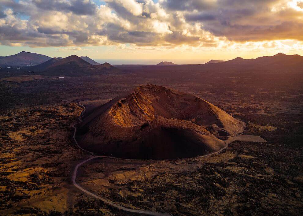 Vue aérienne du Volcan du Cuervo à Lanzarote, avec son cratère illuminé au coucher du soleil.