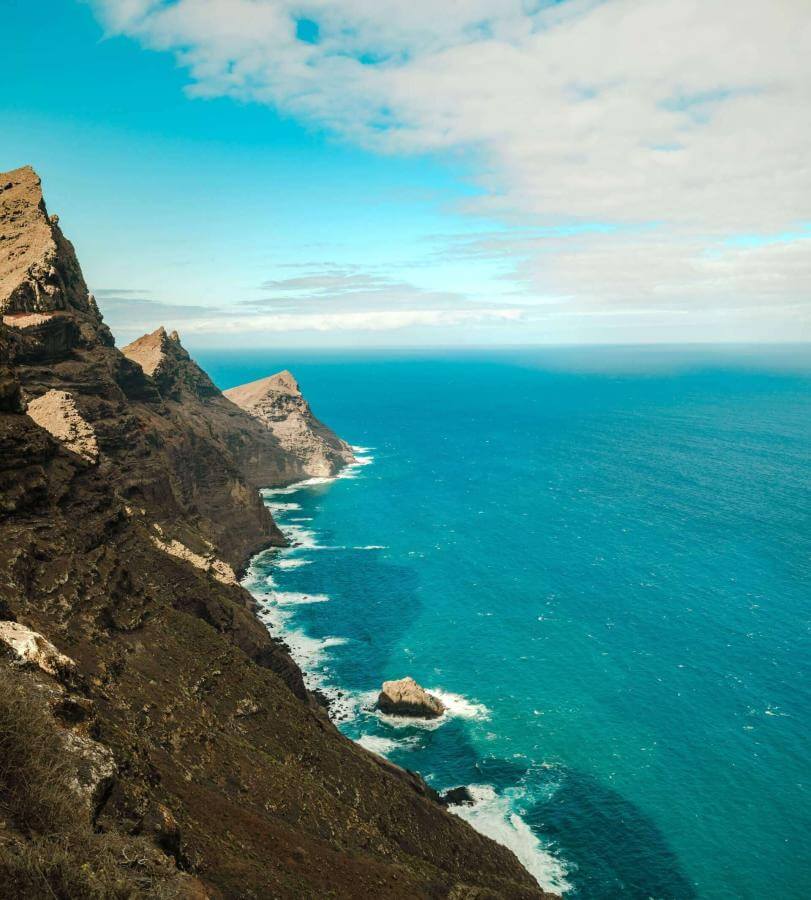 Falaises volcaniques face à l’océan Atlantique sous un ciel semi-nuageux.