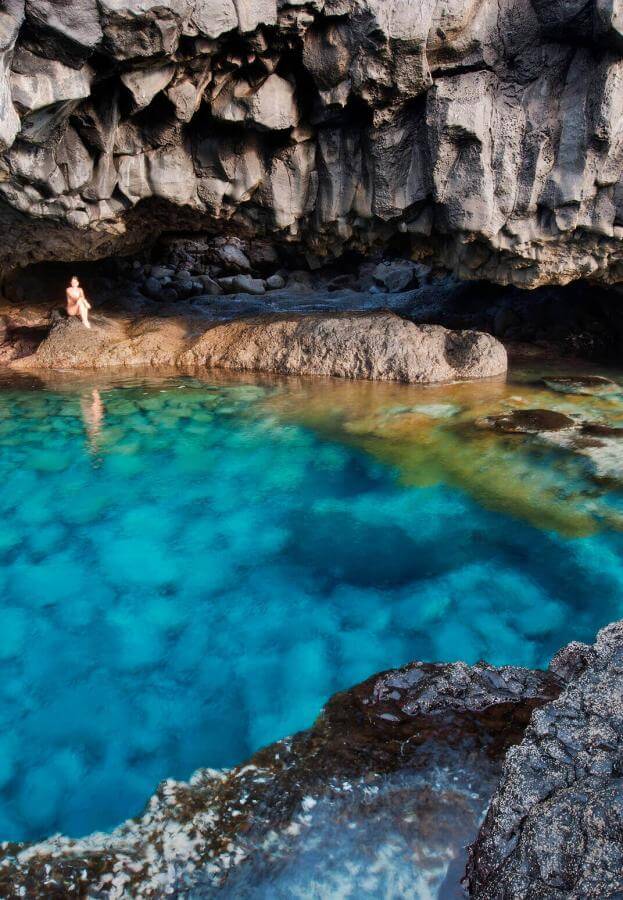 Charco Azul d’El Hierro, un bassin naturel aux eaux turquoise bordé de rochers volcaniques, sous une falaise.