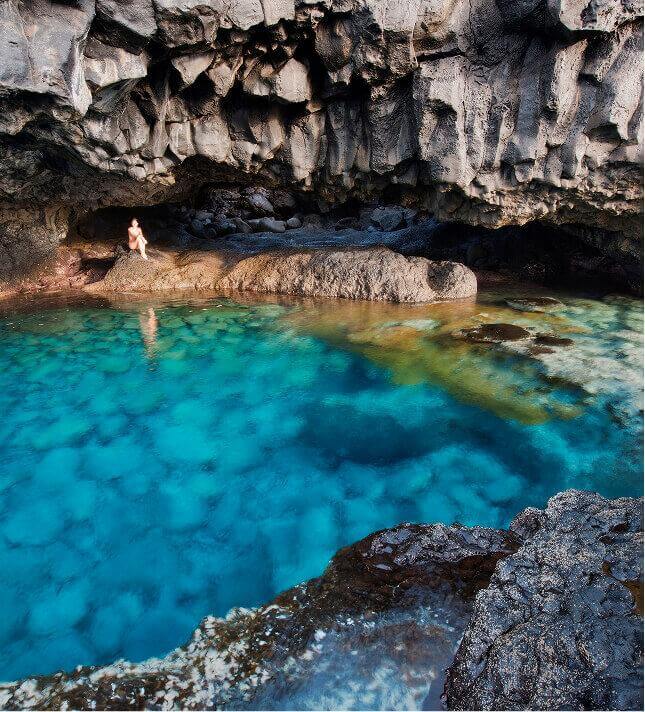 Charco Azul d’El Hierro, un bassin naturel aux eaux turquoise bordé de rochers volcaniques, sous une falaise.