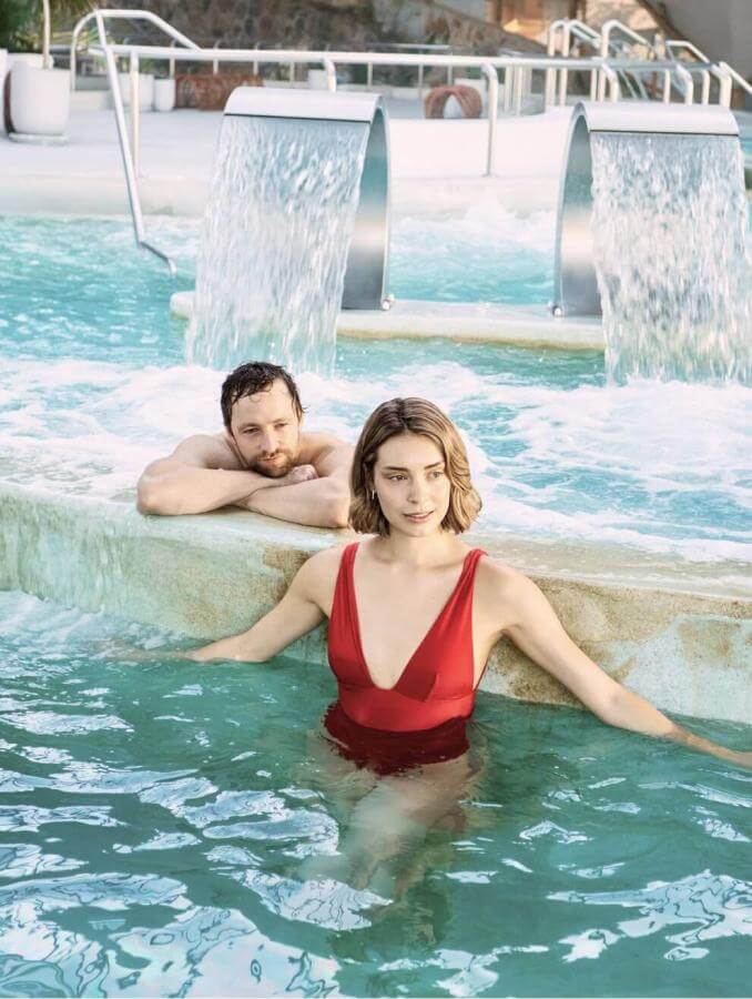 Couple en train de profiter de la piscine de thalassothérapie équipée de jets et de cascades, dans un espace dédié au bien-être et à la détente.